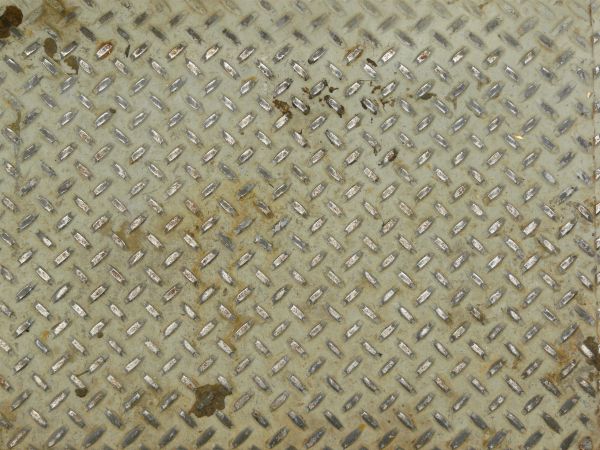 Texture of aged, metal tread with repeating patterns and very worn, dirty surface.